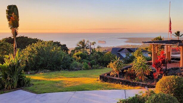A residential property with a view of the ocean, a flag, and a well-maintained garden. - Quiet 3-bedroom house on 2.5 acres w/ocean and town views, 6 beds (Kailua-Kona)