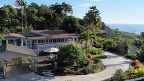 A residential property with a large house, a covered patio, and a landscaped garden. - Quiet 3-bedroom house on 2.5 acres w/ocean and town views, 6 beds (Kailua-Kona)