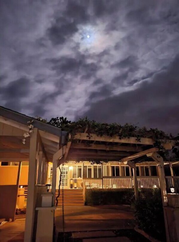 Un espace extérieur abrité, doté d’une terrasse en bois et d’un escalier menant à un bâtiment.