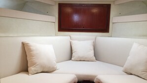 Un banco tapizado blanco con cojines, una mesa de madera y un panel de madera en la parte superior.