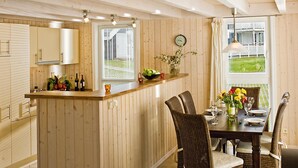 A kitchen with wooden cabinets, a central island with a sink, and a dining area with a table and chairs.