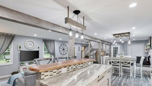 Una cocina amplia con una isla grande, vigas de madera e iluminación colgante.