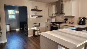 A modern kitchen with white cabinetry, a stainless steel stove, and a large island. - Walking Distance to Aggieville, K-State, and City Park! (Manhattan)