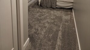 A bedroom with a sloped ceiling, a bed with a gray blanket, a window with curtains, and a carpeted floor. - Walking Distance to Aggieville, K-State, and City Park! (Manhattan)