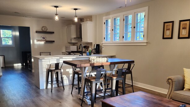 A modern kitchen with white cabinets, a dining area with bar stools, and a ceiling fan. - Walking Distance to Aggieville, K-State, and City Park! (Manhattan)