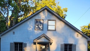 A two-story building with a gabled roof, a front door, and a small porch. - Walking Distance to Aggieville, K-State, and City Park! (Manhattan)
