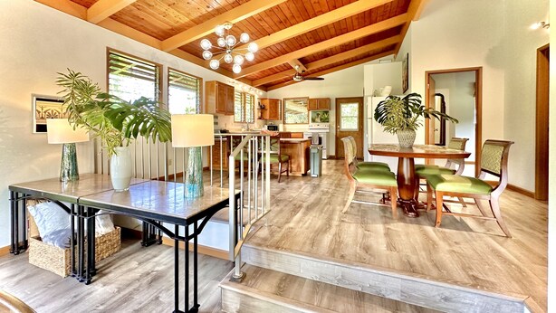 Un vaste espace de vie doté d’un plafond en bois, d’une table à manger avec des chaises et d’un escalier menant à un autre niveau.