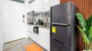 A modern kitchen with white cabinets, a black refrigerator, a patterned backsplash, and a wooden panel wall. - Hyllia by J&J ( Near Airport| Wi-Fi | Netflix )  (Lapu-Lapu City)