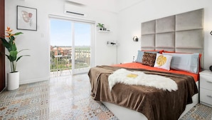 A modern bedroom with a large bed, a balcony, and a city view. - Hyllia by J&J ( Near Airport| Wi-Fi | Netflix )  (Lapu-Lapu City)