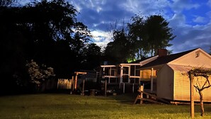 Een woonwijk met een huis, een houten schutting en een gazon onder een gedeeltelijk bewolkte lucht.