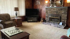 Een gezellige woonkamer met een open haard, een televisie en een comfortabele bank.