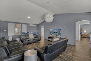 A modern living room with leather sofas, a flat-screen TV, and a large painting.