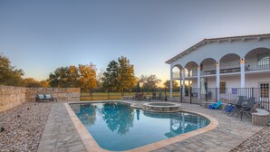Piscina con borde de piedra, rodeada por un patio con mobiliario y una zona cubierta con barandilla.