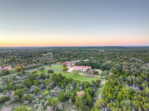 A large estate with multiple buildings, expansive green lawns, and a river.