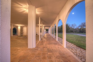 A corridor with arches and a fountain, leading to a building entrance.