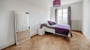 A bedroom with a bed, a nightstand, a mirror, a window with curtains, and a radiator. - Am Pavillon Bed & Kitchen (Bern)