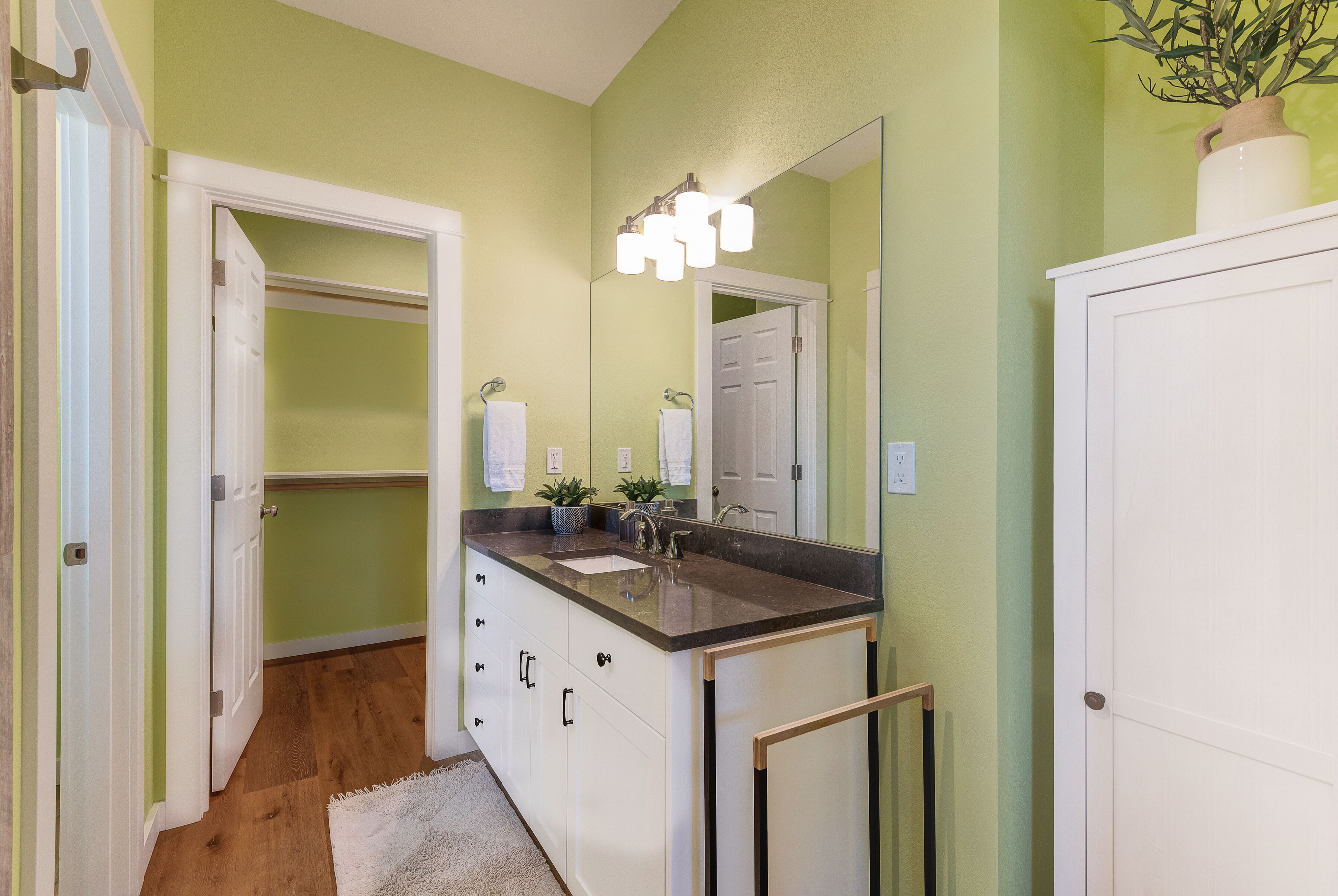 A bathroom with a vanity, sink, and mirror. There are two towels hanging on the wall.