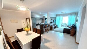 A modern apartment with a dining area, kitchen, and living room. - 314, Excelente Apartamento Para Desfrutar Férias (Bombinhas)