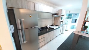 A modern kitchen with stainless steel appliances, wooden cabinets, and a black countertop. - 314, Excelente Apartamento Para Desfrutar Férias (Bombinhas)
