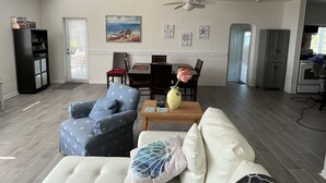 A living room with a sofa, armchair, coffee table, and dining area. - Charming 2 bed, 2 bath cottage 100 feet from private sandy ocean beach (Islamorada)