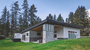 Uma casa moderna com fundação de pedra, grandes janelas e uma área de varanda coberta.