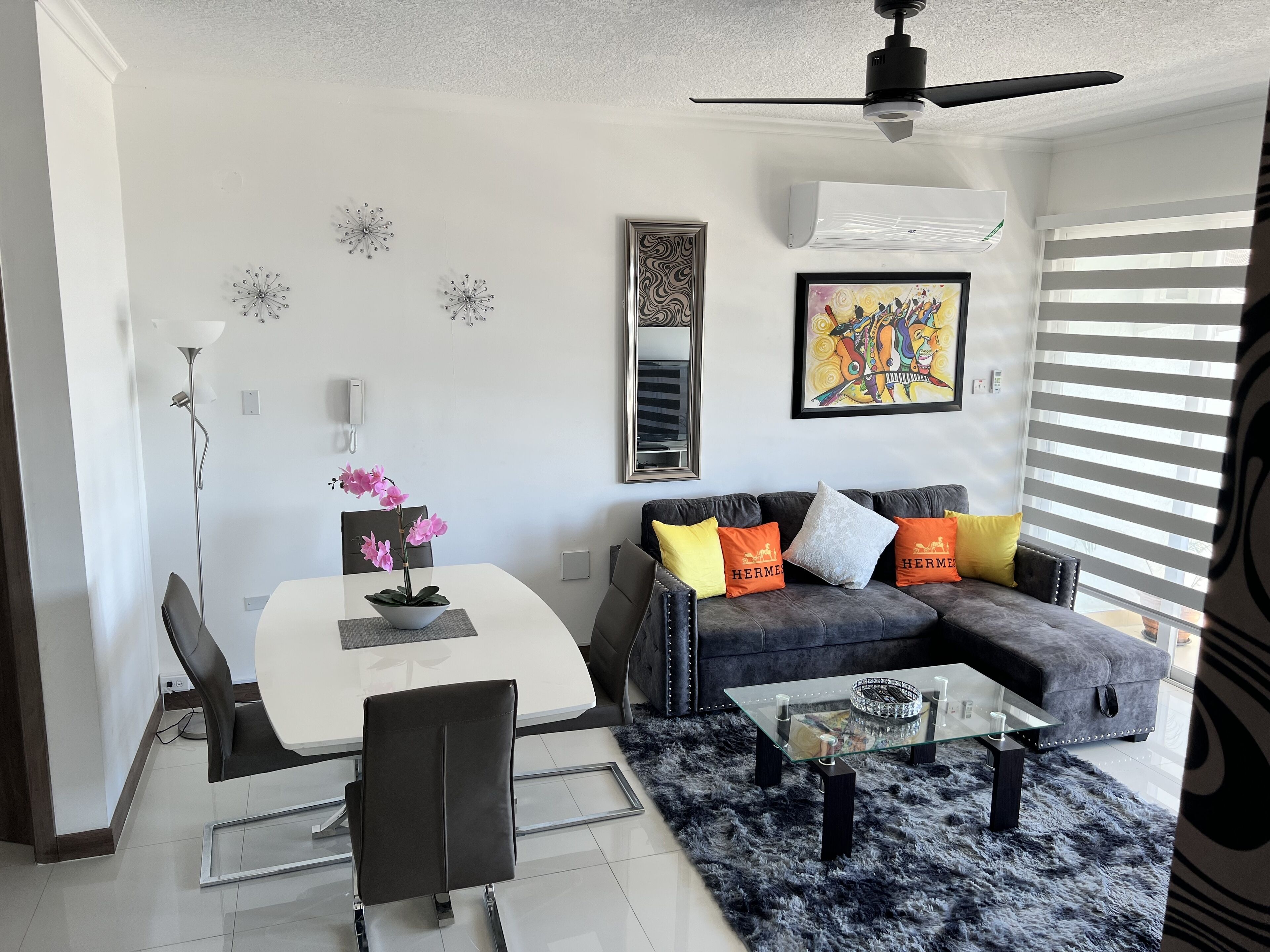 A modern living room with a dining area, featuring a sofa, coffee table, and a dining table with chairs.