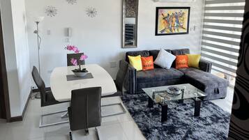 A modern living room with a dining area, featuring a sofa, coffee table, and a dining table with chairs.