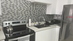 Una cocina moderna con salpicadero de azulejos blanco y negro, electrodomésticos de acero inoxidable y armarios blancos.