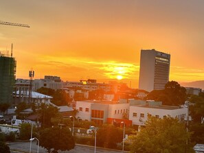 A cityscape at sunset with a prominent high-rise building and various other structures. - Gated Luxury New Kingston 1 Bdrm Condo Pool & Gym (Kingston)