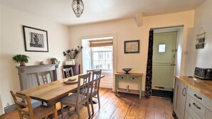 A dining area with a wooden table and chairs, a small side table with a bowl, and a vintage-style refrigerator. - Spacious 3 bed apartment with castle view (Harlech)