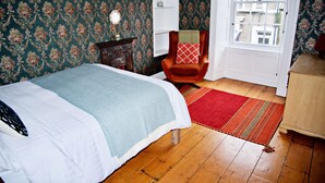 A bedroom with a bed, a chair, a dresser, and a window. - Spacious 3 bed apartment with castle view (Harlech)