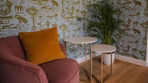A room with a red sofa, a small white table, and a large green plant.