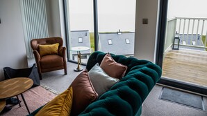 A modern living room with a green sofa, a brown leather armchair, and a small round table.