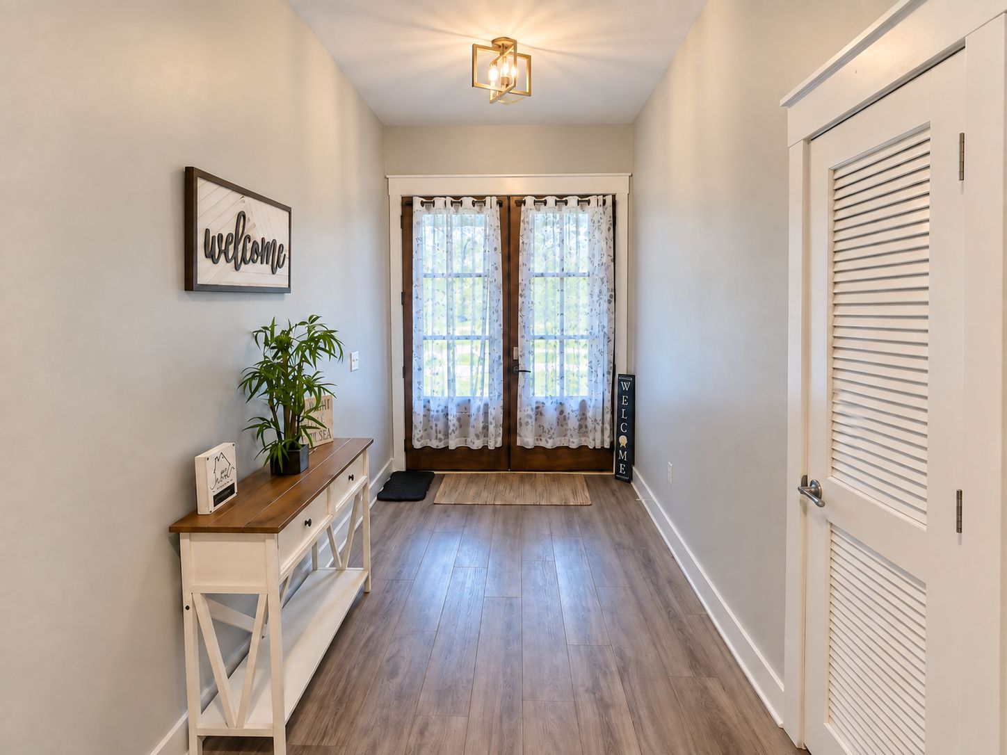 A hallway with a wooden bench, a welcome sign, and a potted plant.