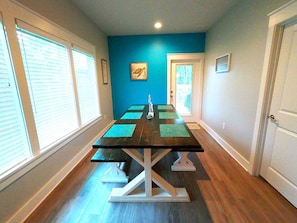 Relax in this serene space with a long table, white walls, and a blue accent wall, featuring a large window and a door.