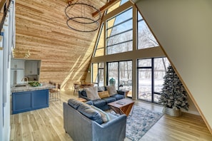 A spacious loft with a high ceiling, large windows, a cozy seating area, and a kitchen with a blue island. - Stunning A-frame cabin on Maud Lake ( Near Detroit Lakes ) (Audubon)