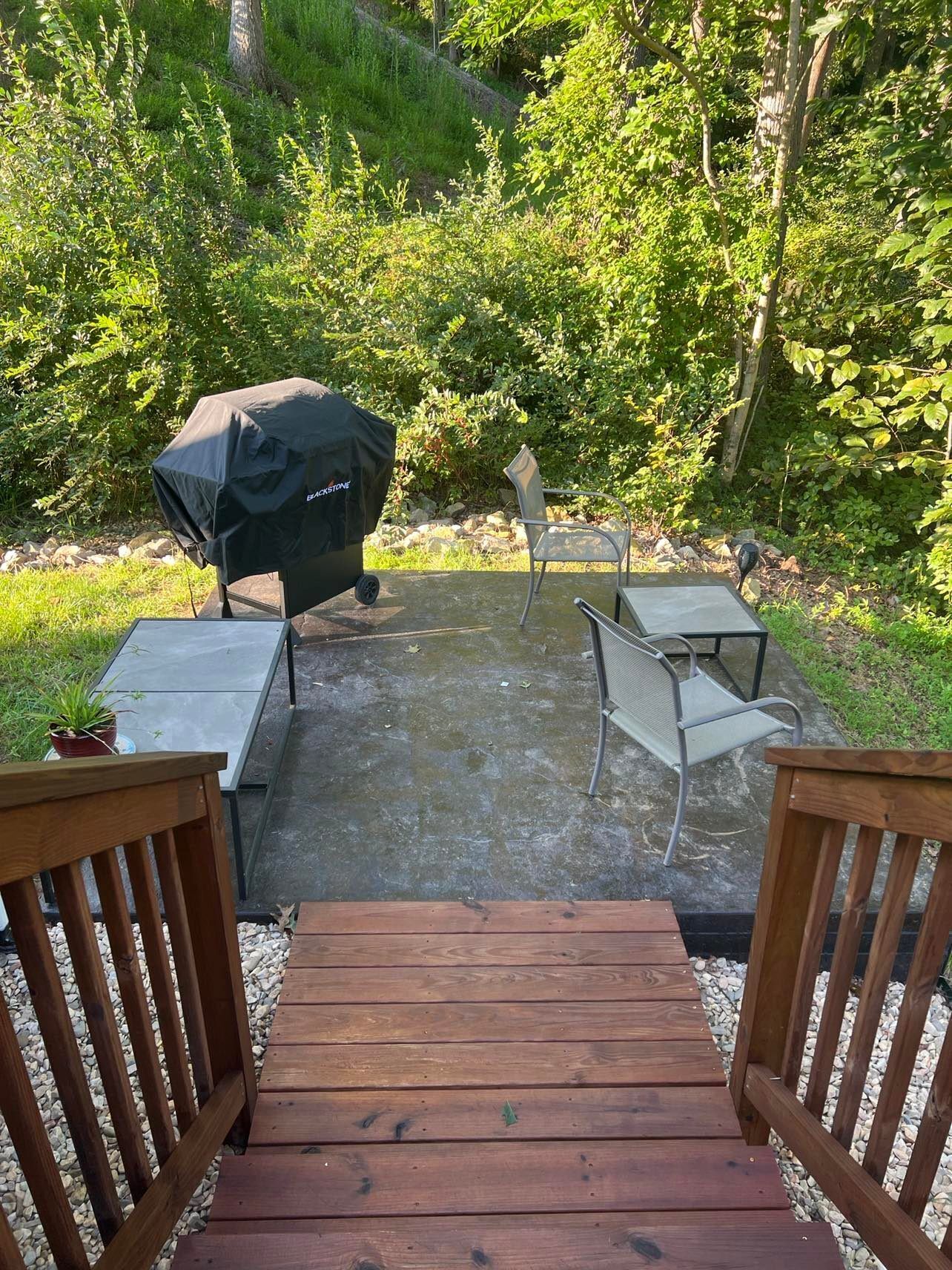A patio with a grill, chairs, and a small table.