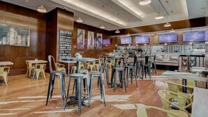 Un restaurant aux murs en bois, doté de nombreuses tables et chaises, et éclairé par des suspensions.