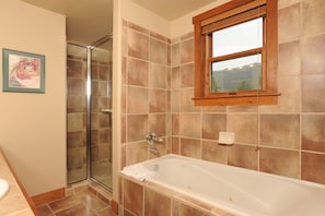 A bathroom with a glass shower enclosure, a bathtub, and a window with a view.
