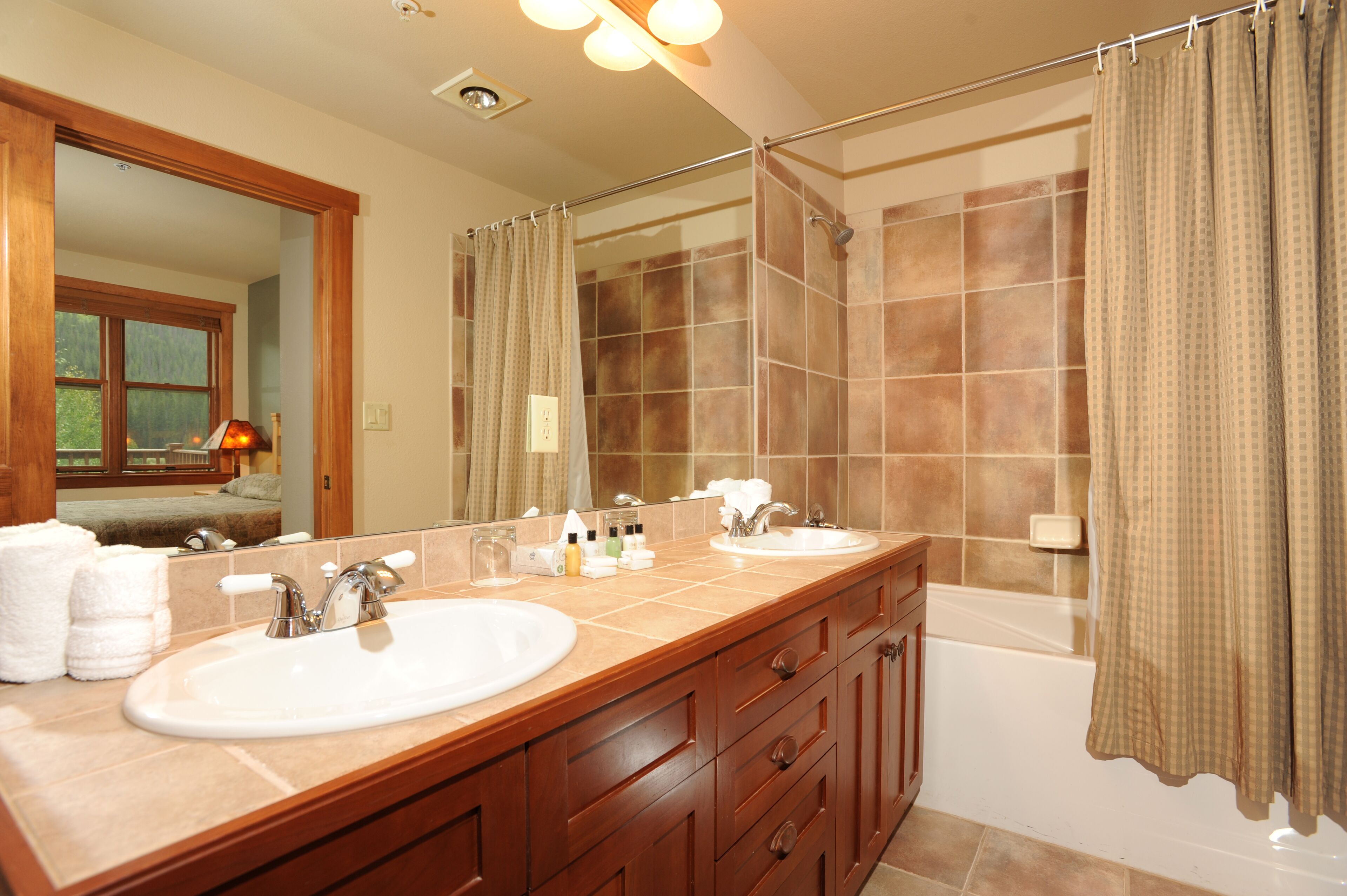 Une salle de bain avec deux lavabos, un miroir, un rideau de douche et une baignoire.