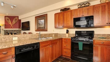A kitchen with granite countertops, wooden cabinets, a dishwasher, a stove, and a microwave.