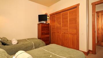 A bedroom with two beds, a TV on a dresser, and a wooden closet.