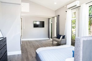 A bedroom with a bed, a TV mounted on the wall, a grey sofa, and a window with curtains. - Cozy House With Patio, Fireplace, Parking - Hollywood, Florida (Hollywood)