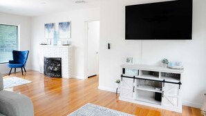 A modern living room with a fireplace, a mounted TV, and a white entertainment unit.
