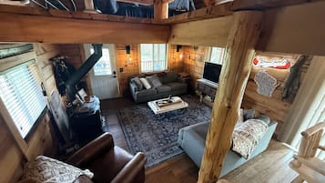 A cozy cabin interior with a sofa, armchair, and a fireplace.