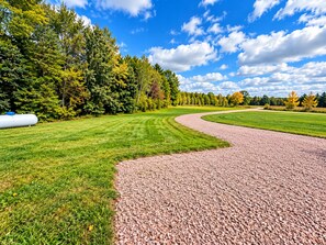 Ein Kiesweg schlängelt sich durch einen Park mit Rasenflächen und Bäumen.