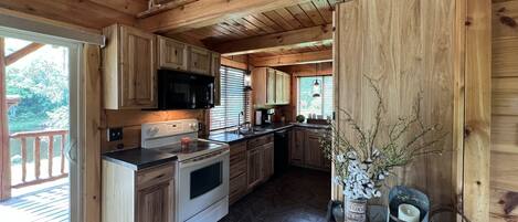 Cozinha de cabana de madeira com fogão, micro-ondas e armários.