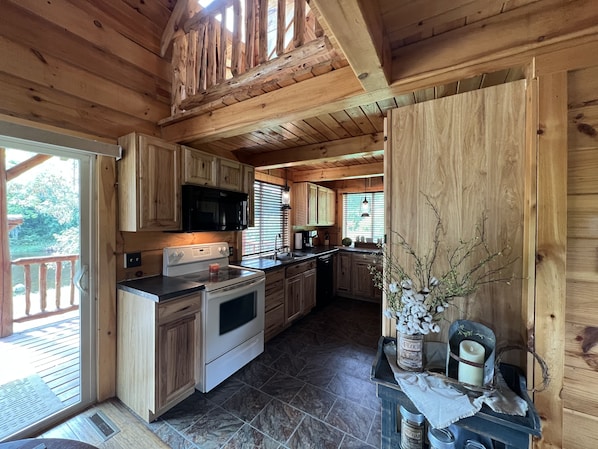 Cocina de cabaña de madera con estufa, microondas y armarios.