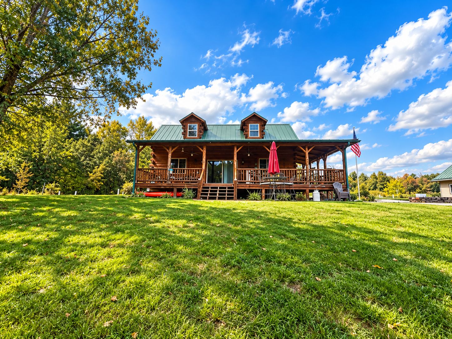 A log cabin with a porch, a covered deck, and an American flag.