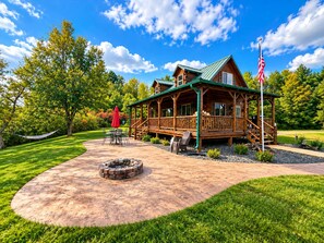 A wooden cabin with a porch, a fire pit, and a flag. - Relax at The Lincoln Log Cabin perched along the Jump River. (Sheldon)